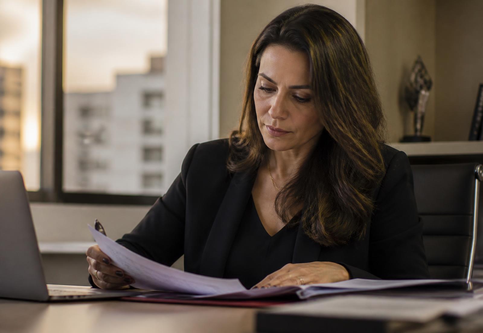 Profissional revisando documentos sozinha em um escritório no fim do dia